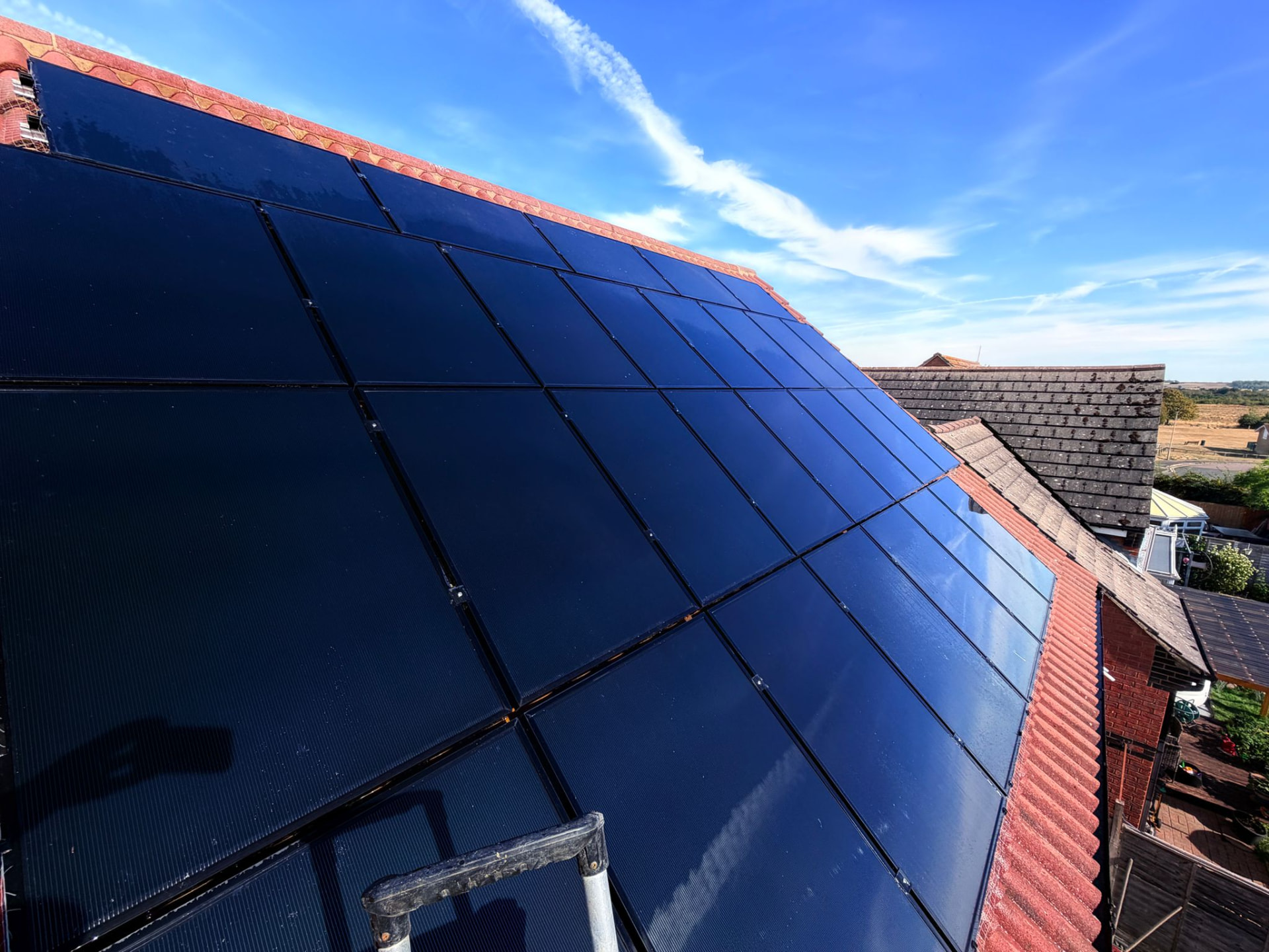 The same roof-mounted solar panel array after cleaning, with the dark panels now glossy, reflective and free of bird droppings and grime.